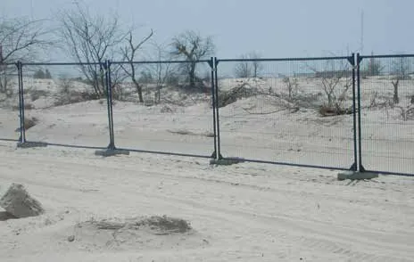 Temporary mesh fence panels on bases across sand dunes